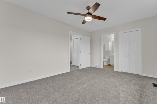Neutral wall paint with gray carpeting, featuring a ceiling fan with light fixture, white interior doors, and a double-door closet - 2912 31 Street Nw, Edmonton, AB 