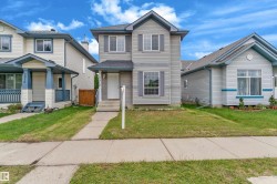 Two-story residence with siding exterior, multi-pane windows, and a paved walkway leading to the front entry - 