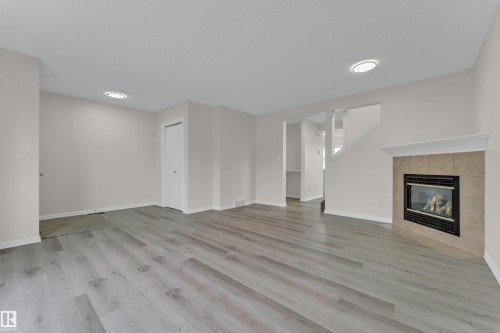 Spacious interior featuring wood-finish flooring, recessed lighting, and a fireplace with a tile surround and mantel - 2912 31 Street Nw, Edmonton, AB 