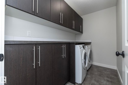 Laundry area featuring dark wood-finish cabinetry, a solid surface countertop, and tile flooring - 53/55 Michigan Street, Devon, AB 