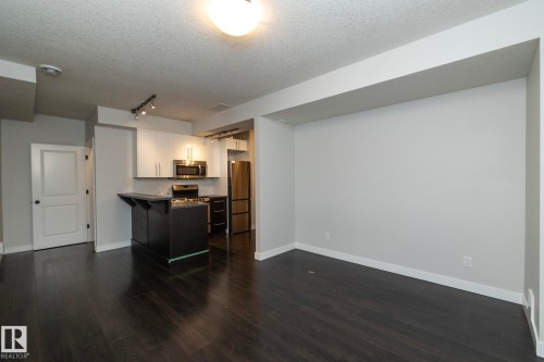 Dark wood-finish flooring throughout, complemented by light-toned walls - 53/55 Michigan Street, Devon, AB 