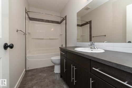 Dark wood-finish vanity with a built-in sink and a large mirror - 53/55 Michigan Street, Devon, AB 
