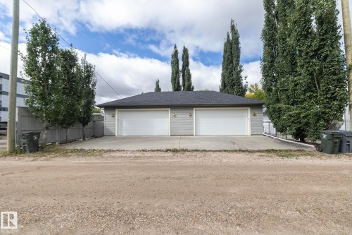Detached garage with two white overhead doors, light gray siding, and a dark shingle roof - 53/55 Michigan Street, Devon, AB 