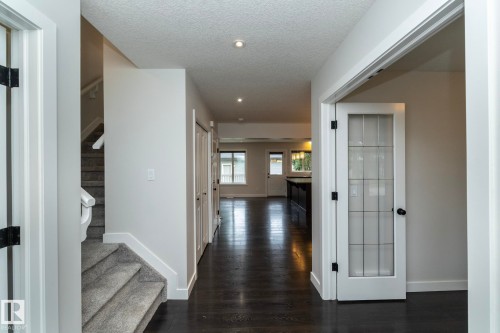 Hallway with dark wood-finish flooring, recessed lighting, and a white door with glass paneling - 53/55 Michigan Street, Devon, AB 