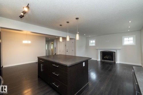 Kitchen island with dark cabinetry and a stone-finish countertop - 53/55 Michigan Street, Devon, AB 