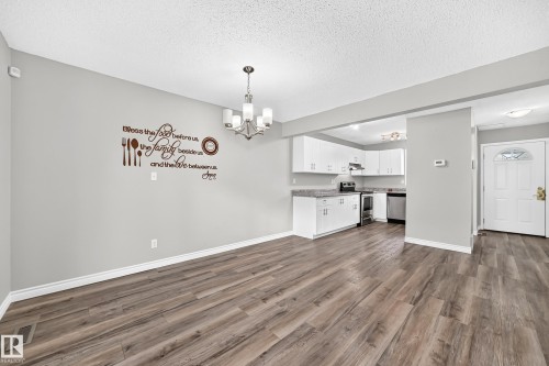 Wood-finish flooring, recessed lighting, white cabinetry, light countertops, and a white front door with decorative glass inserts - 18146 81 Avenue Nw, Edmonton, AB 
