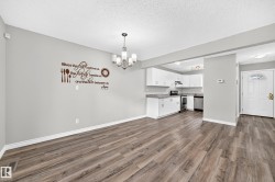 Wood-finish flooring, recessed lighting, white cabinetry, light countertops, and a white front door with decorative glass inserts - 