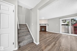Living space featuring a stone-clad fireplace, wood-finish flooring, and sliding glass doors - 