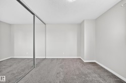 Wall-to-wall mirrored closet doors, neutral wall paint, and gray textured carpeting - 