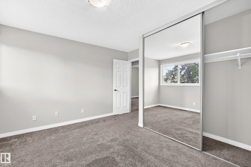 Wall-to-wall carpeting with light gray walls, mirrored closet doors, and built-in closet shelving - 18146 81 Avenue Nw, Edmonton, AB 