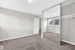 Wall-to-wall carpeting with light gray walls, mirrored closet doors, and built-in closet shelving - 