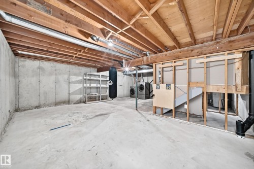 Unfinished basement featuring concrete walls and flooring, exposed wood joists, and a partial framing structure - 18146 81 Avenue Nw, Edmonton, AB 