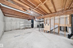 Unfinished basement featuring concrete walls and flooring, exposed wood joists, and a partial framing structure - 
