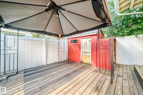 Wood-finish deck with a red storage shed and white privacy fencing - 18146 81 Avenue Nw, Edmonton, AB 