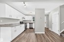 Kitchen featuring white cabinetry, stone-finish countertops, stainless steel appliances, and wood-finish flooring - 18146 81 Avenue Nw, Edmonton, AB 