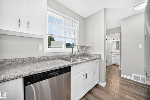 Kitchen featuring white cabinetry, a dual basin stainless steel sink with a high-arc faucet, a stainless steel dishwasher, and a light-toned countertop - 18146 81 Avenue Nw, Edmonton, AB 