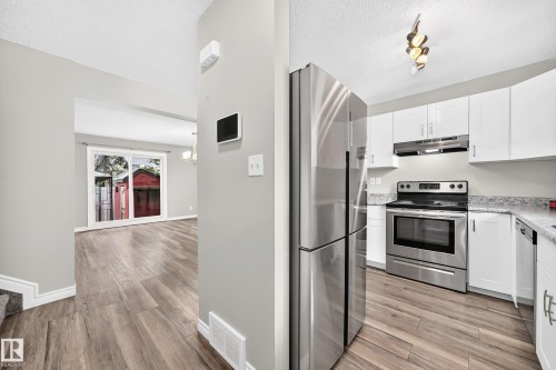 Modern kitchen with stainless steel appliances, white cabinetry, and light-toned countertops - 18146 81 Avenue Nw, Edmonton, AB 