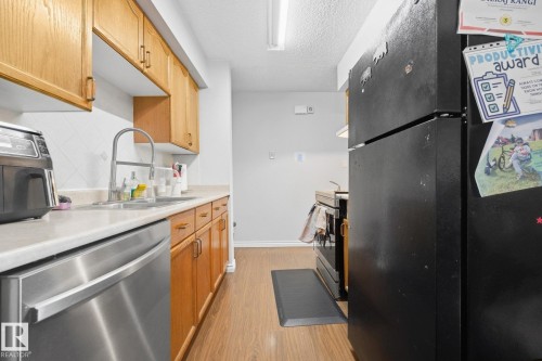 Wood-finish flooring, stainless steel dishwasher, white countertop, tile backsplash, and wood cabinetry - #2 14120 80 St Nw, Edmonton, AB 
