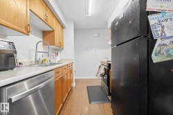 Wood-finish flooring, stainless steel dishwasher, white countertop, tile backsplash, and wood cabinetry - 