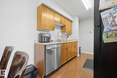 Wood-finish flooring, light wood cabinetry, stainless steel dishwasher, and a white countertop - #2 14120 80 St Nw, Edmonton, AB 