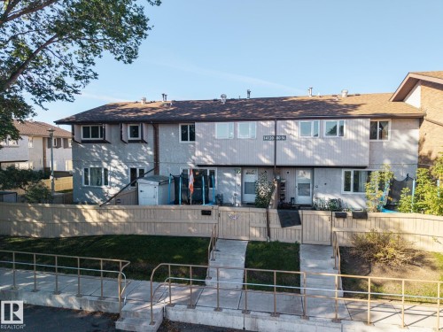 Two-story stucco and siding facade with multiple windows, private fenced yard, and a shingle roof - #2 14120 80 St Nw, Edmonton, AB 