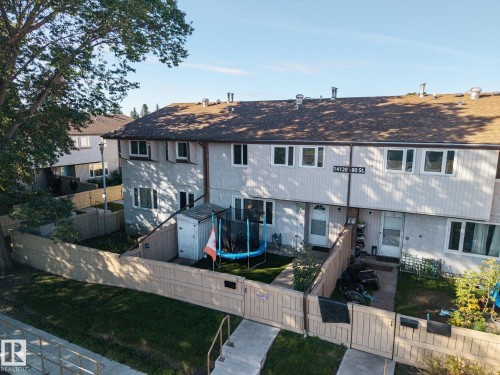 Pitched roof with asphalt shingles, light-colored exterior siding, fenced backyard, concrete walkway, and dedicated front entries - #2 14120 80 St Nw, Edmonton, AB 