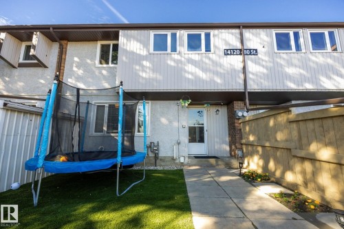 Exterior featuring light-colored siding, a white entry door, and multiple windows - #2 14120 80 St Nw, Edmonton, AB 