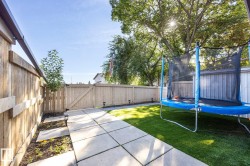 Enclosed backyard featuring a privacy fence with gate, paver pathway, and artificial turf - 