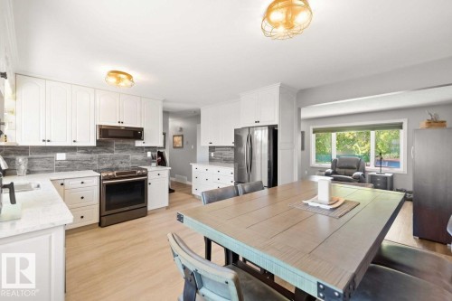 White cabinetry with dark hardware, stainless steel appliances, stone tile backsplash, wood-finish flooring, and recessed lighting - 13427 83 Street Nw, Edmonton, AB 