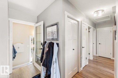 Wood-finish flooring, white panel doors, and a glass-paneled entry door, complemented by a semi-flush mount ceiling fixture - 13427 83 Street Nw, Edmonton, AB 