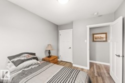 Wood-finish flooring, white trim throughout, and white interior doors with black hardware - 