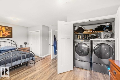 Wood-finish flooring throughout, bright white ceilings with flush-mount lighting, and a dedicated laundry closet with a stacked washer and dryer - 13427 83 Street Nw, Edmonton, AB 