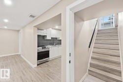 Contemporary kitchen featuring white cabinetry, stainless steel range, gray tile backsplash, and light wood-finish flooring - 