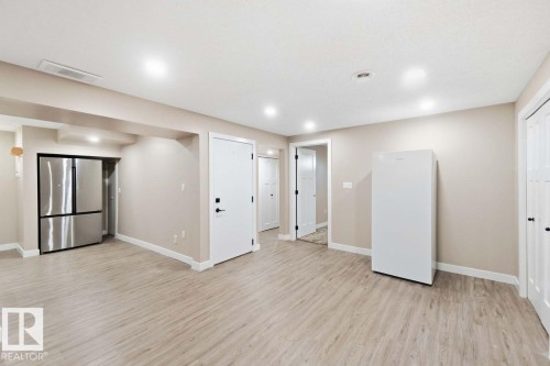 Spacious open-concept basement featuring wood-finish flooring throughout, recessed lighting, and multiple white interior doors - 13427 83 Street Nw, Edmonton, AB 
