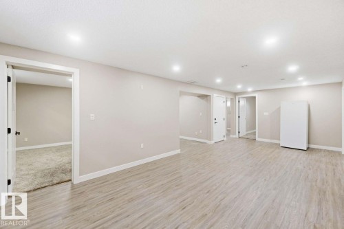 Spacious room featuring light wood-finish flooring, recessed lighting, and multiple doorways - 13427 83 Street Nw, Edmonton, AB 