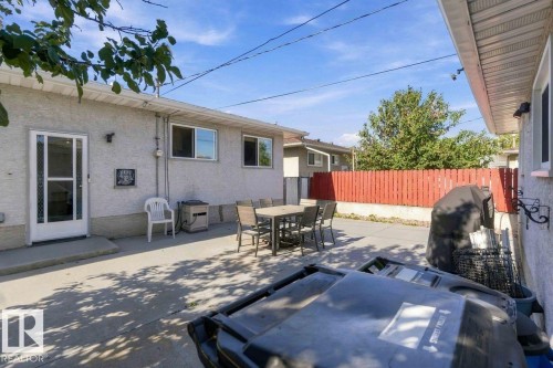 Poured concrete patio with stucco exterior, multiple windows, and a red picket fence - 13427 83 Street Nw, Edmonton, AB 