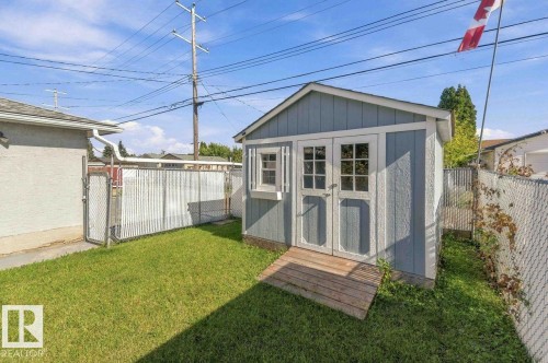 Detached storage shed featuring double doors, a window, and wood-finish siding - 13427 83 Street Nw, Edmonton, AB 