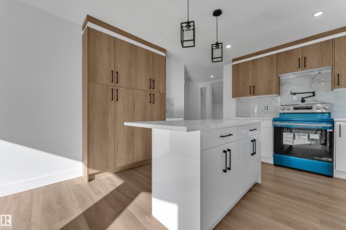 White kitchen island with a solid surface countertop, wood-finish flooring, full-height wood-finish cabinetry, white upper and lower cabinetry, and recessed lighting - 3320 43 Street Nw, Edmonton, AB 