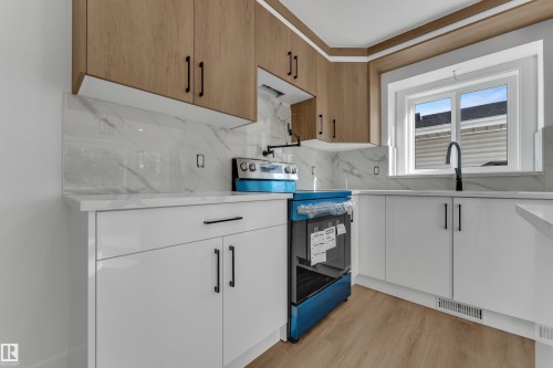 Two-tone cabinetry with wood-finish upper cabinets and white lower cabinets, solid-surface countertops, and a full tile backsplash - 3320 43 Street Nw, Edmonton, AB 