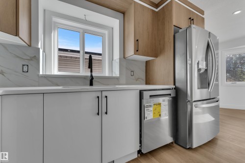 Stainless steel refrigerator, integrated dishwasher, and wood-finish upper cabinetry - 3320 43 Street Nw, Edmonton, AB 