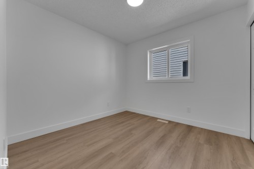 Light wood-finish flooring, white walls, and a single window with white trim - 3320 43 Street Nw, Edmonton, AB 