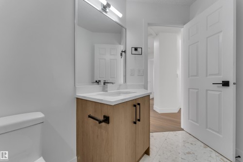 Bathroom featuring a light-toned wood-finish vanity with a white countertop and rectangular undermount sink - 3320 43 Street Nw, Edmonton, AB 