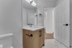 Bathroom featuring a light-toned wood-finish vanity with a white countertop and rectangular undermount sink - 