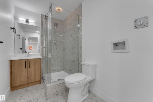 Glass-enclosed shower with a recessed light, wood-finish vanity with a white countertop, and a wall-mounted mirror with integrated lighting - 3320 43 Street Nw, Edmonton, AB 