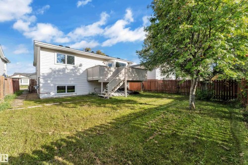 Expansive backyard featuring a mature tree, privacy fencing, and a two-story exterior with a deck - 3320 43 Street Nw, Edmonton, AB 