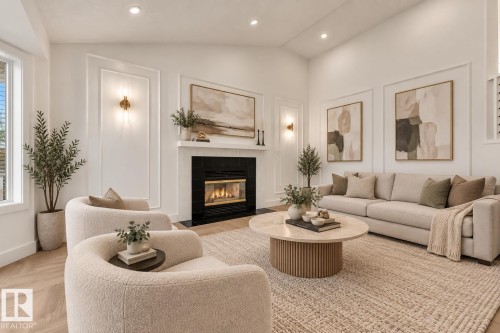 Vaulted ceiling with recessed lighting, wood-finish flooring, fireplace with black tile surround, decorative wall molding, and wall sconces - 3320 43 Street Nw, Edmonton, AB 