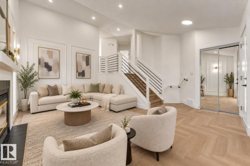 Herringbone wood-finish flooring, staircase with black metal railings, fireplace with black tile surround, recessed lighting, and mirrored closet doors - 3320 43 Street Nw, Edmonton, AB 