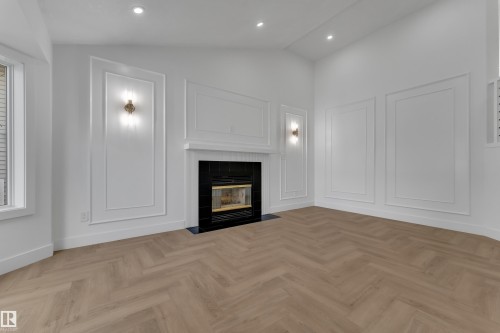 Living space featuring a fireplace with a black surround, herringbone wood-finish flooring, recessed lighting, and decorative wall molding - 3320 43 Street Nw, Edmonton, AB 