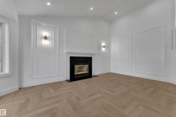 Living space featuring a fireplace with a black surround, herringbone wood-finish flooring, recessed lighting, and decorative wall molding - 