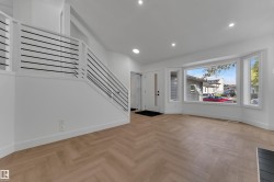 Herringbone wood-finish flooring, contemporary staircase with horizontal metal balusters, recessed lighting, and a bay window - 